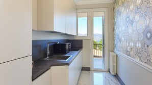 A modern kitchen with a black microwave, a sink, and a window leading to a balcony.