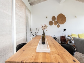 A wooden dining table with a vase of dried flowers, a white tray, and a bicycle in the background. - Olea White Studio 6, Tavira, Algarve (Querença)