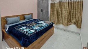 A bedroom with a bed, a wardrobe, a ceiling with recessed lighting, and a window with curtains. - Himalayan View stay Shehar wala ghar (Dehradun)