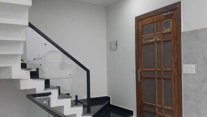 A modern staircase with glass railings and a black handrail, leading to a landing with a black tray. - Himalayan View stay Shehar wala ghar (Dehradun)