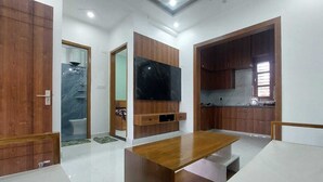 A modern kitchen with wooden cabinets, a black countertop, and a built-in oven. - Himalayan View stay Shehar wala ghar (Dehradun)