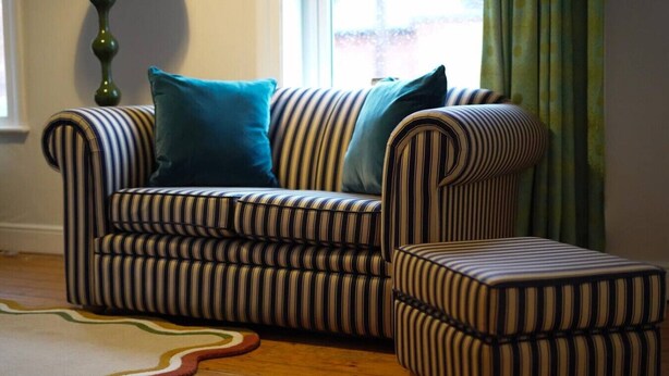 A striped sofa and ottoman in a room with a wooden floor and a green curtain. - The Linden Lodge; nr Cathedral, with parking (Lincolnshire)