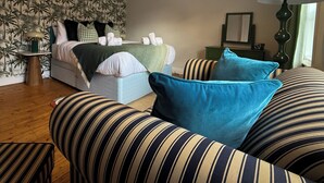 Een slaapkamer met een bed, een gestreept slaapbankje en een groene lamp.