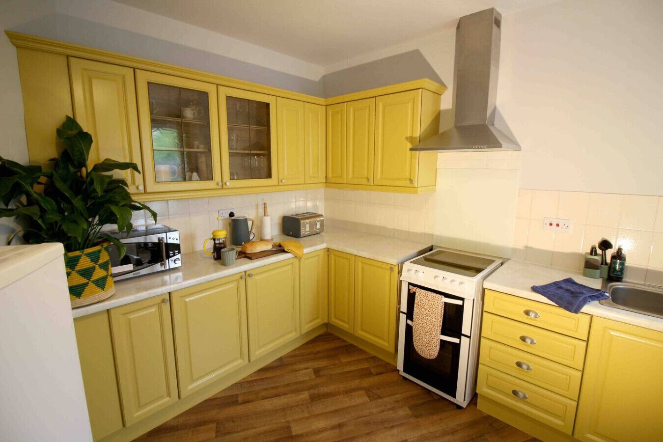 A kitchen with yellow cabinets, a stove, a microwave, and a sink.