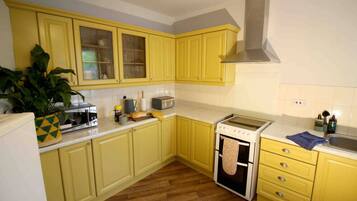 A kitchen with yellow cabinets, a stove, a microwave, and a sink.