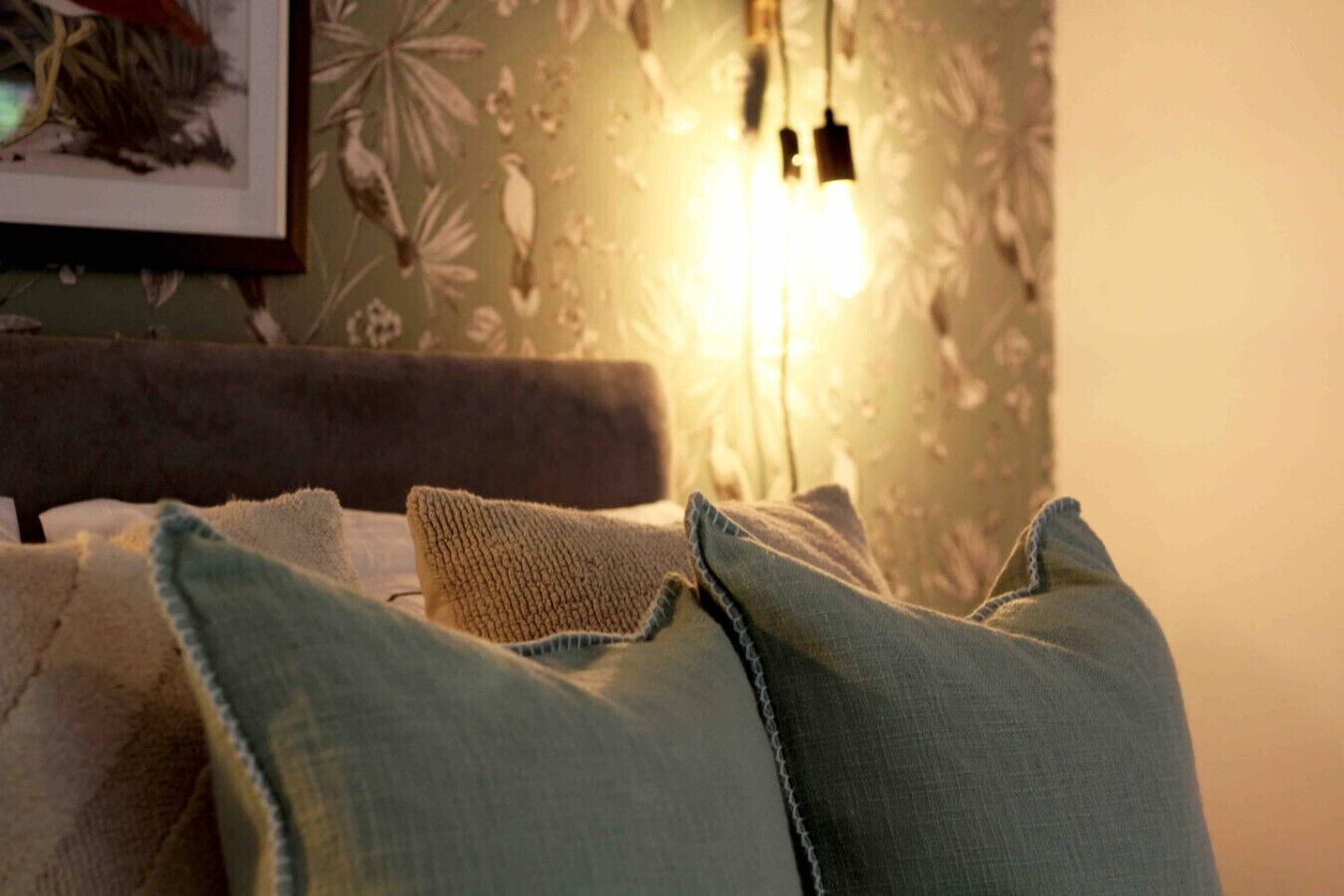 Une pièce confortable avec un lit, des oreillers et un luminaire fixé au mur.