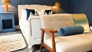 A bedroom with a white bed, a beige armchair, a blue rug, and two bedside lamps. - The Maple House common views, central Lincoln (Lincolnshire)