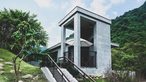 Ein modernes Gebäude mit Betonfassade, einer überdachten Treppe und Blick auf üppiges Grün.