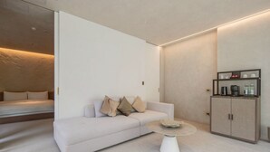 Ein modernes Hotelzimmer mit einer Couch, einem Couchtisch und einem Schrank mit Annehmlichkeiten.