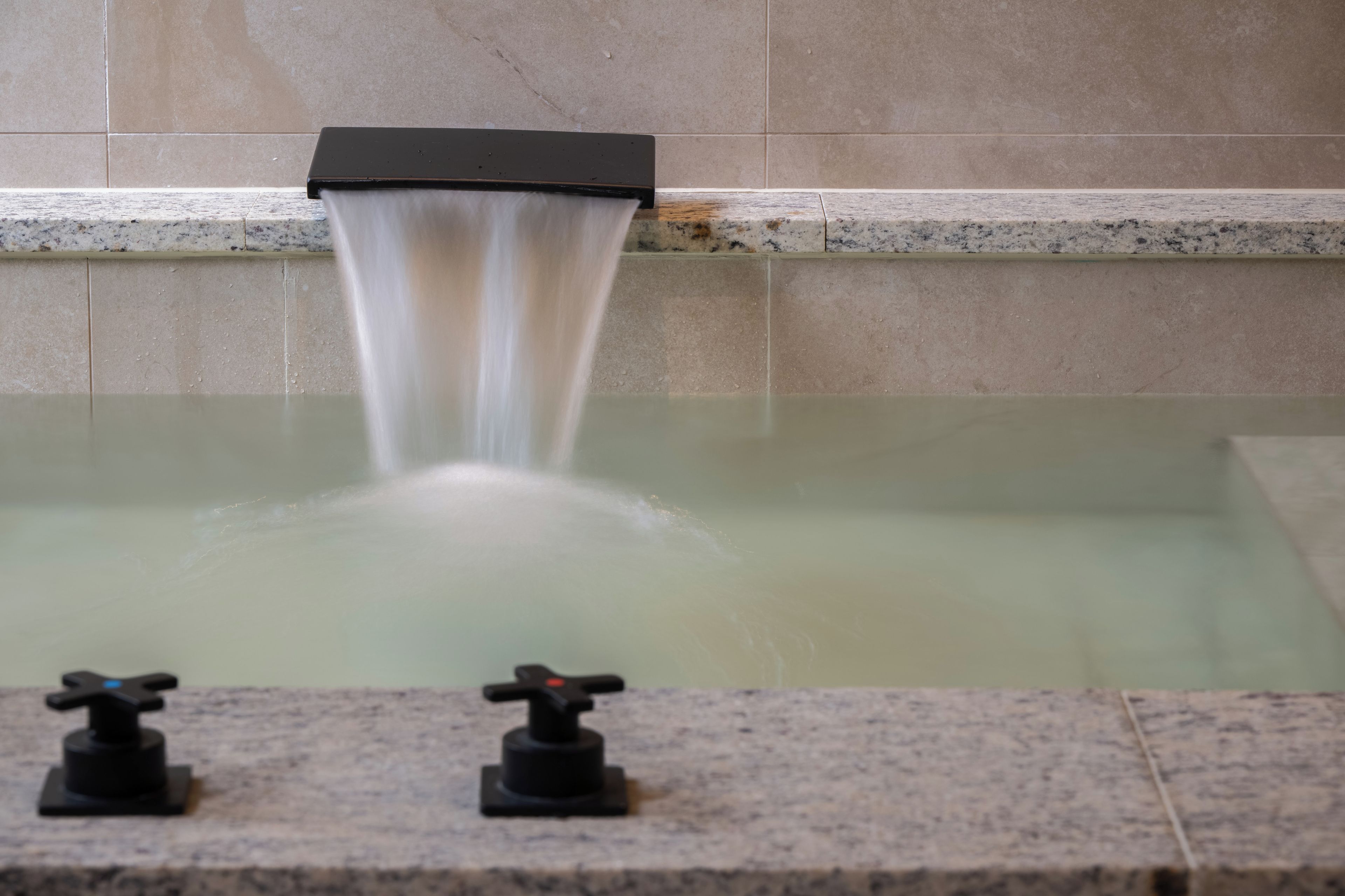 A bathtub with a faucet and a control knob.
