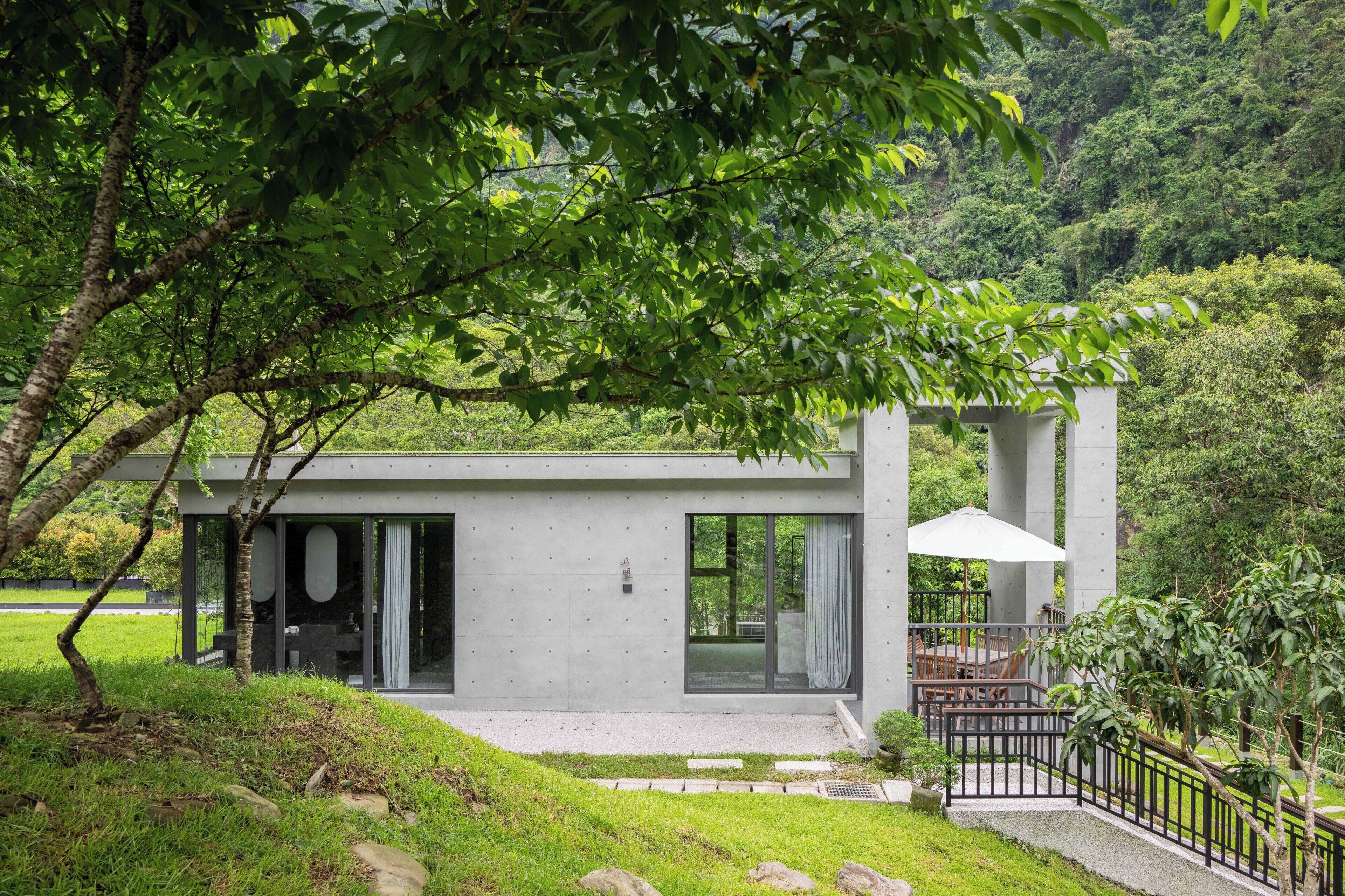 A modern house with a flat roof, large windows, and a patio area with outdoor furniture.