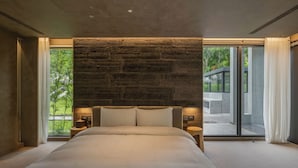 Ein modernes Schlafzimmer mit einem großen Bett, einer Steinwand und großen Fenstern.