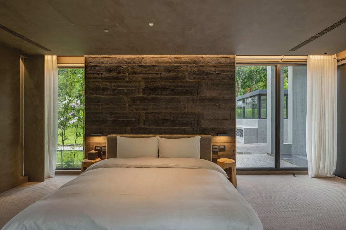 Een moderne slaapkamer met een groot bed, stenen muur en grote ramen.
