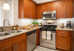 A kitchen with wooden cabinets, stainless steel appliances, a granite countertop, and a potted plant. - Cozy 1-bedroom Marina Living (Marina del Rey)
