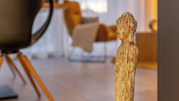 Une sculpture représentant une figure humaine, placée dans un intérieur moderne, avec un arrière-plan flou.