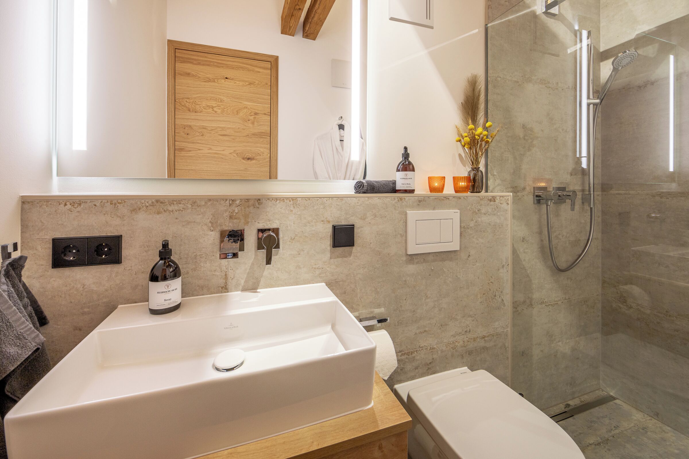 Une salle de bain moderne avec un grand lavabo blanc, une douche en verre et un meuble-lavabo en bois.