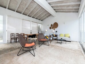 Ampla sala de estar com teto alto, mesa de jantar e sofá.