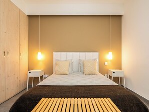 Ein modernes Schlafzimmer mit einem großen Bett, zwei Nachttischen und einem Kleiderschrank.