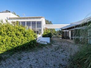 A modern house with a large glass window, a covered outdoor area, and a gravel driveway. - Olea Yellow Studio 7, Tavira, Algarve (Querença)