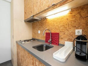 Eine Küche mit Holzwand, Spüle aus Edelstahl, einer roten Kücheninsel und einer Kaffeemaschine.
