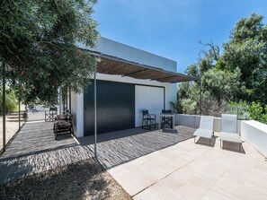 A modern outdoor patio with a pergola, seating area, and a garage door. - Olea Yellow Studio 7, Tavira, Algarve (Querença)