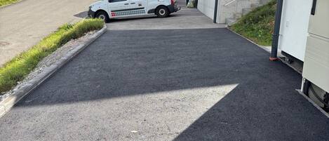 Una camioneta blanca estacionada frente a un edificio con una rampa que conduce a una puerta.