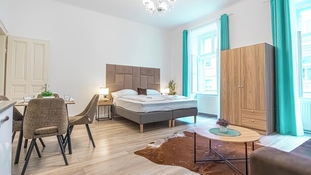 Een moderne hotelkamer met een bed, een zithoek, een houten garderobe en uitzicht op de stad.