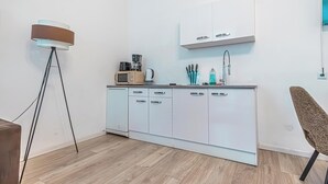 Een moderne keuken met witte kastjes, een aanrecht en een koffiezetapparaat.