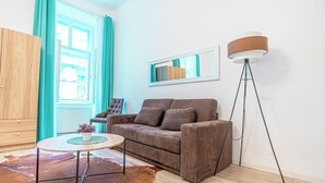Een moderne woonkamer met een bruine bank, een ronde salontafel, een vloerlamp en een grote spiegel aan de muur.