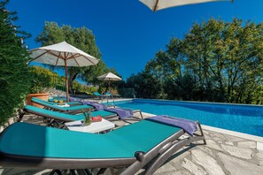 A poolside area with lounge chairs, umbrellas, and a clear blue pool. - MOLUNAT DUBROVNIK (Gornji Brgat)