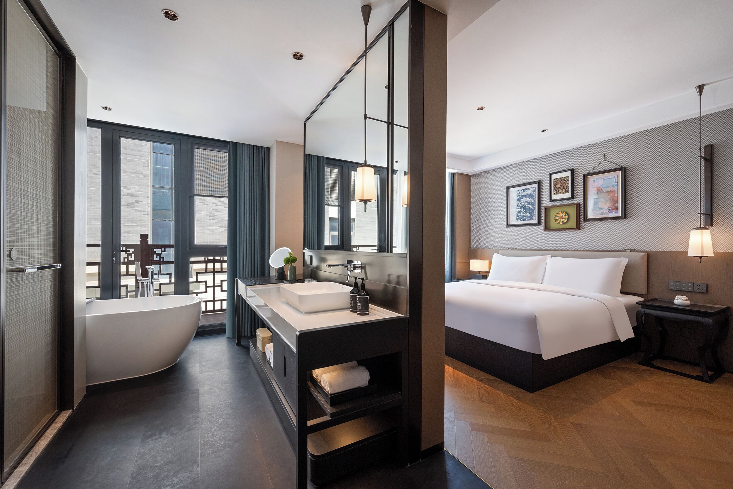 Une salle de bain d’hôtel moderne avec une baignoire sur pieds, un grand miroir et un meuble-lavabo.