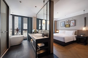 Un baño de hotel moderno con una bañera independiente, un espejo grande y un tocador con lavabo.