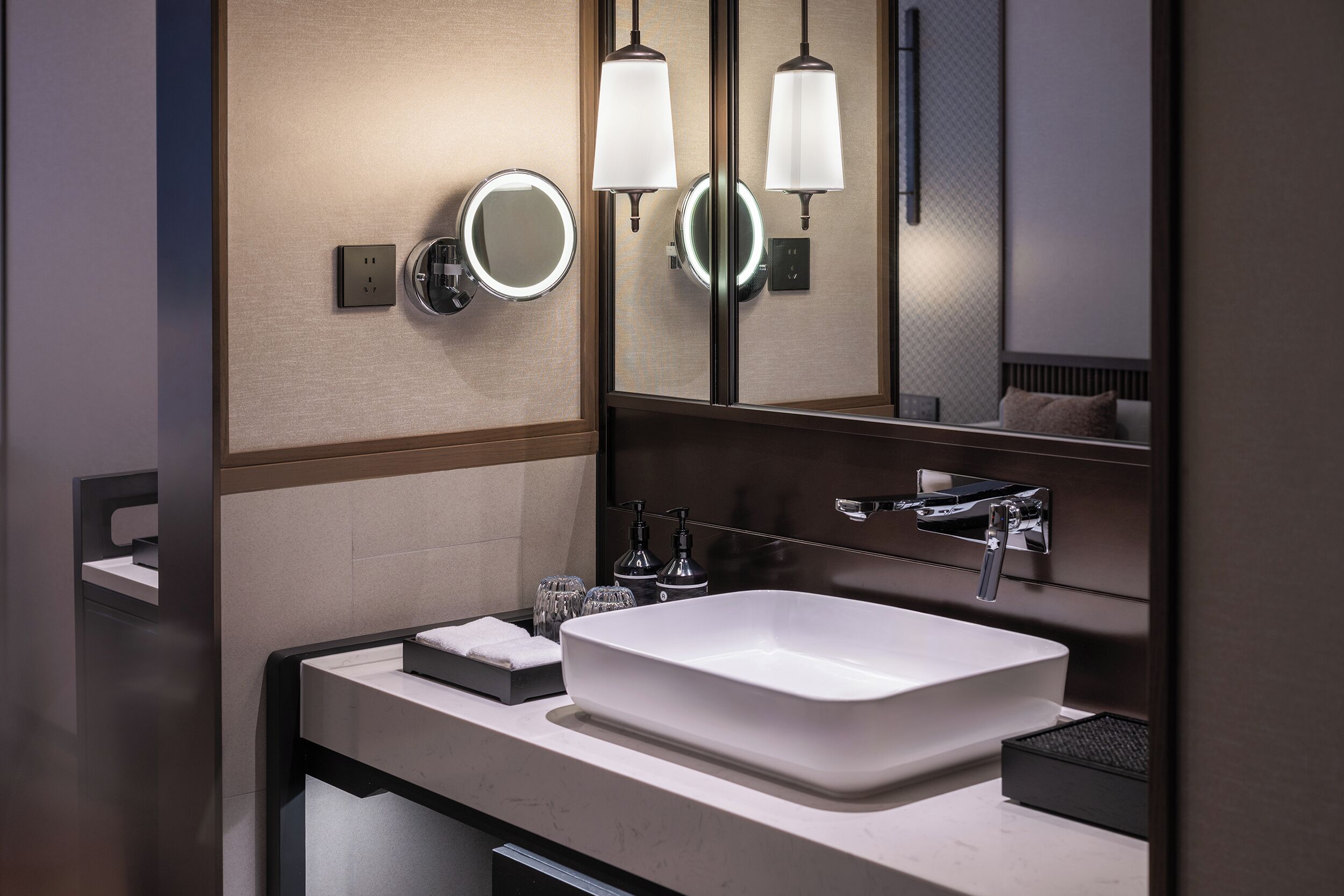 A modern bathroom with a large rectangular sink, two wall-mounted mirrors, and a towel rack.
