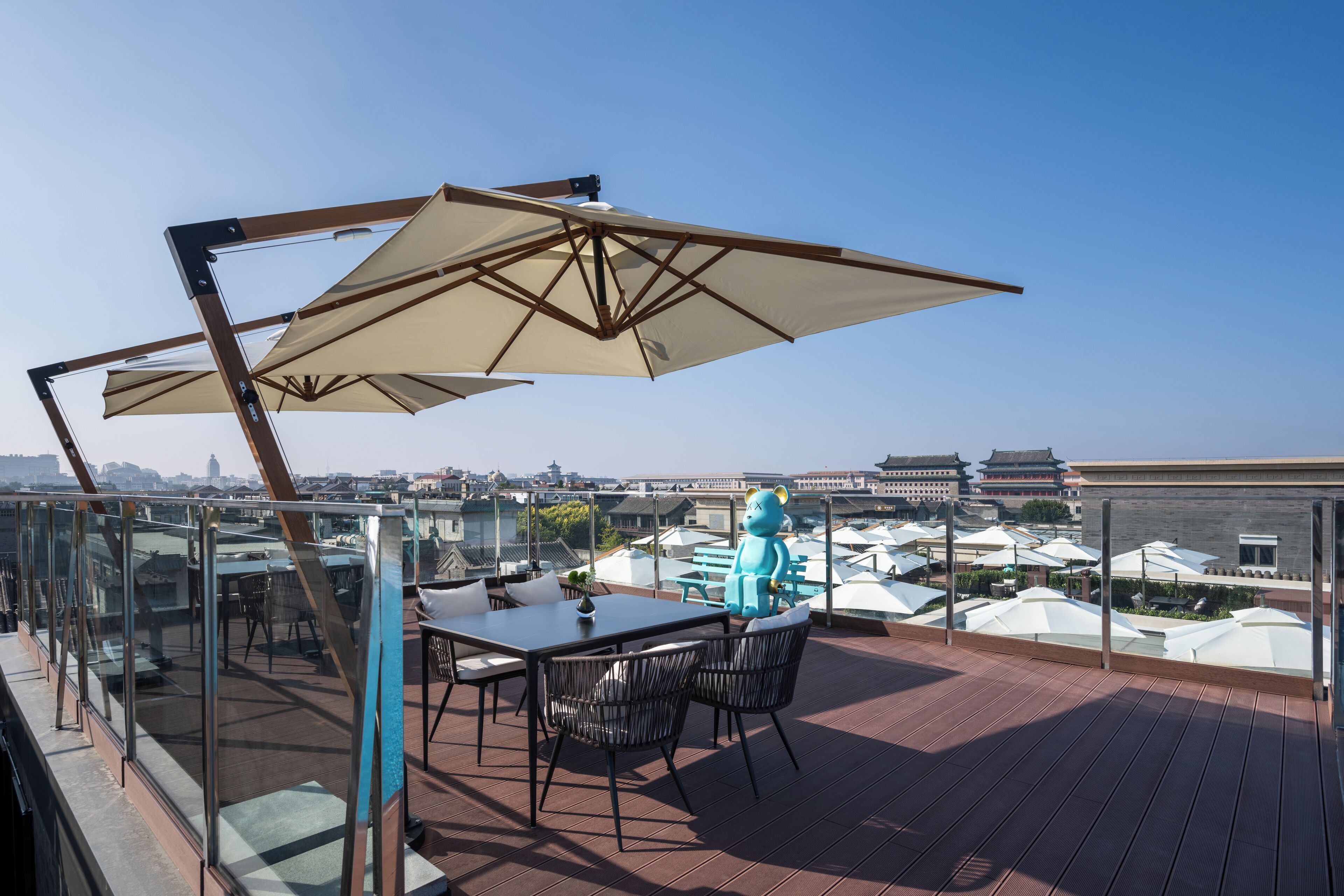 Eine Dachterrasse mit Tisch und Stühlen, einem großen Sonnenschirm und Blick auf eine Stadtlandschaft.