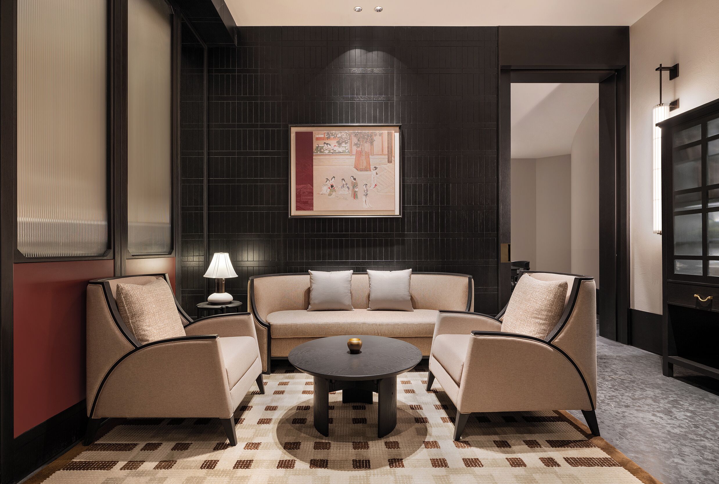 A modern living room with a sofa, two armchairs, a coffee table, and a framed artwork on the wall.