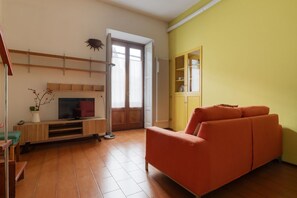 A living room with a sofa, TV, wooden shelves, and a cabinet. - GuestHost - Cozy 30sqm studio apartment located on the third floor of a typical Milanese ringhiera building with elevator.The property is set in a strategic area, just a few minutes walk from the “Gerusalemme” & “Domodossola” metro stops (M5 Lila (Milan)