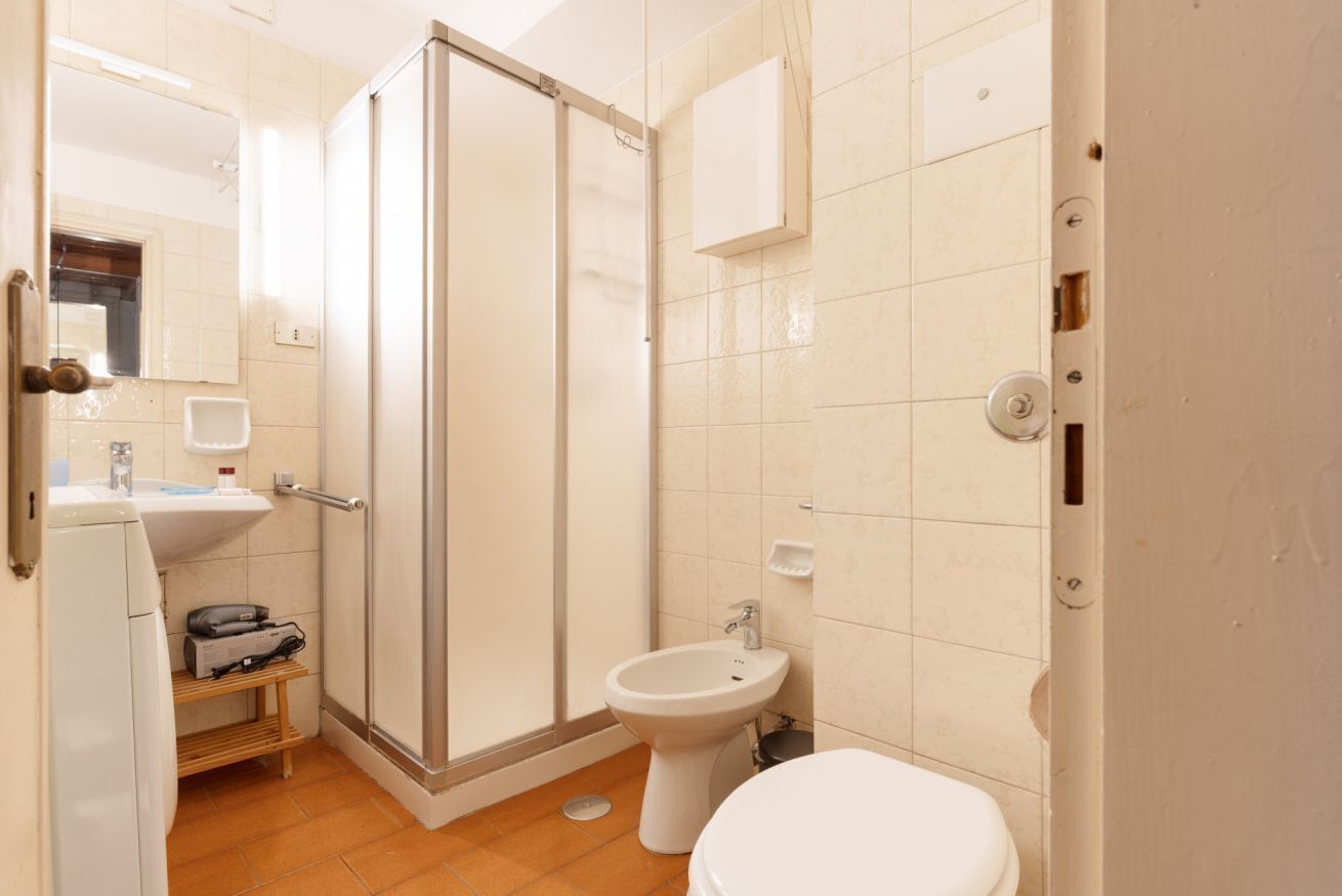 A bathroom with a shower, toilet, sink, and a mirror.