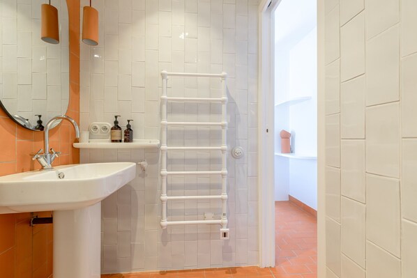 Une salle de bain avec un lavabo blanc, un miroir et un porte-serviettes.