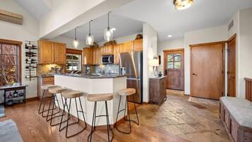 A spacious kitchen with a central island, wooden cabinets, stainless steel appliances, and pendant lighting.