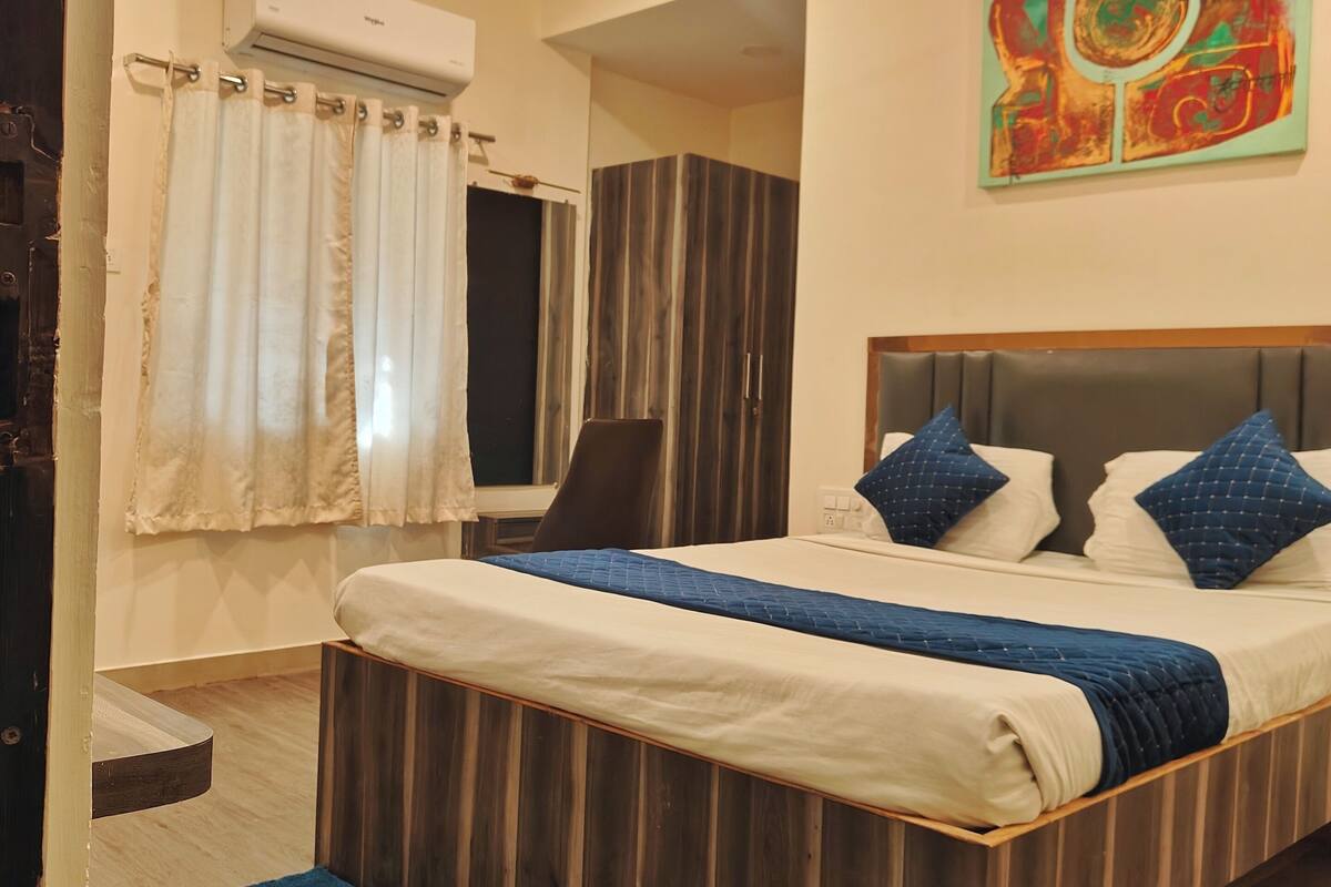 Ein Schlafzimmer mit Bett, Deckenventilator, Fenster mit Vorhängen und einer Wand-Klimaanlage.