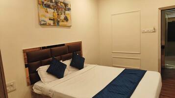 Uma cama bem arrumada com um cobertor acolchoado e duas almofadas, uma cabeceira de madeira e um quadro na parede.