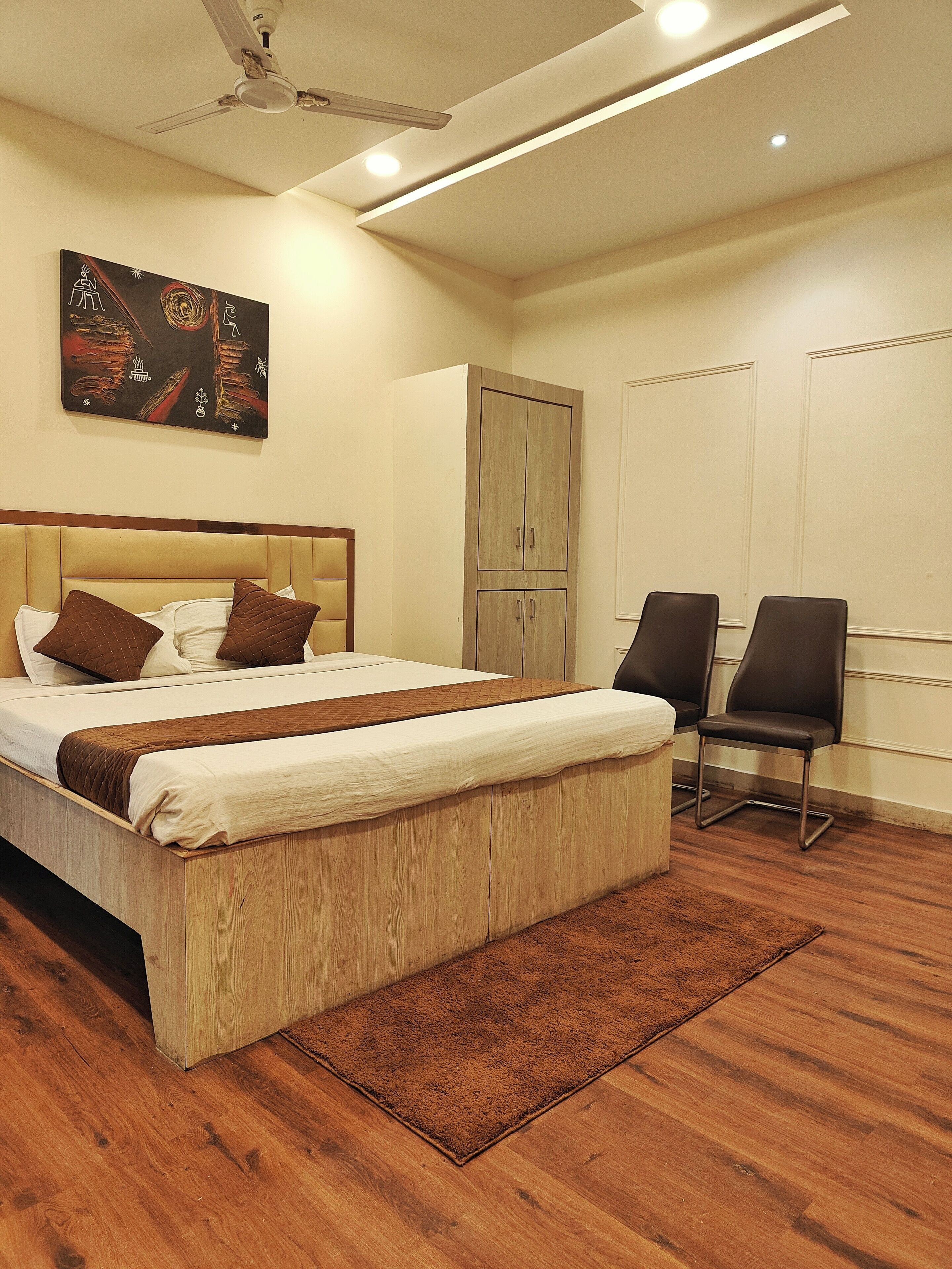 Un dormitorio con cama, dos sillas, un armario y un ventilador de techo.