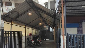Ein überdachter Parkbereich mit gefliestem Boden, einem Motorrad und einem Tor.