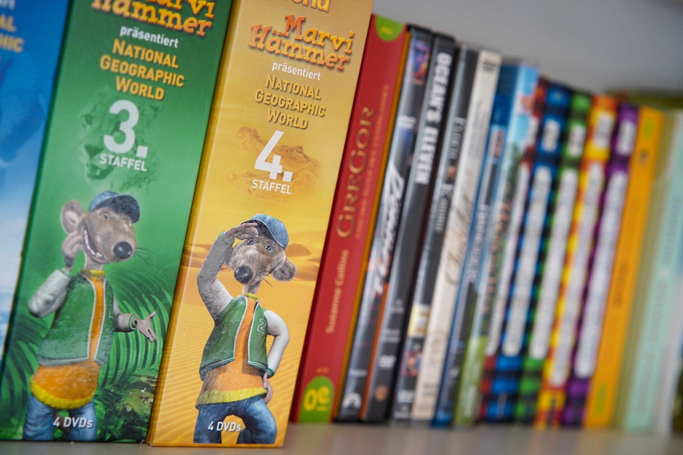 Una fila de libros en una estantería, incluyendo los volúmenes 3 y 4 de 'National Geographic World' y otros libros de colores.