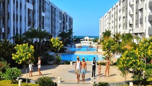 Un complex turístic amb piscina, palmeres i vistes a l'oceà.