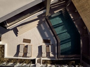 Ein modernes Gebäude mit Swimmingpool, Lounge-Bereich und Liegestühlen sowie einem markanten architektonischen Design.