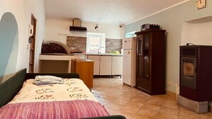 A compact room with a bed, a kitchenette, a wooden cabinet, and a wood-burning stove. - In the typical Ligurian village beautiful apartment with sea view (Valeriano)