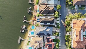 Luchtbeeld van een kustgebied met woningen, een steiger en een weg.