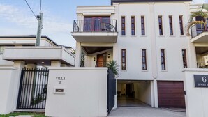 Een modern gebouw met twee verdiepingen, een hek, balkons en een garage.