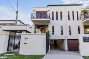 A modern two-story building with a gated entrance, balconies, and a garage. - 4 BR 3R | Pool | Deck | Water Canal Outlook (Surfers Paradise)